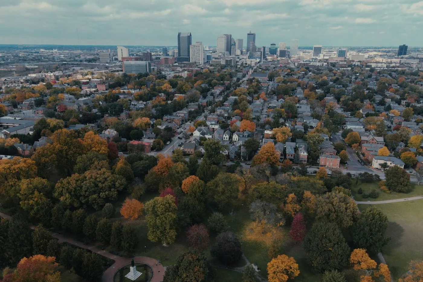Aerial view of tree-lined Columbus neighborhoods in the fall, with downtown in the distance