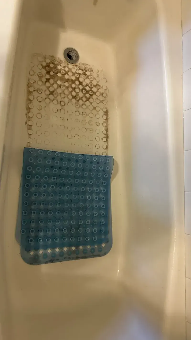 Before: the bathtub with a bath mat, dirty