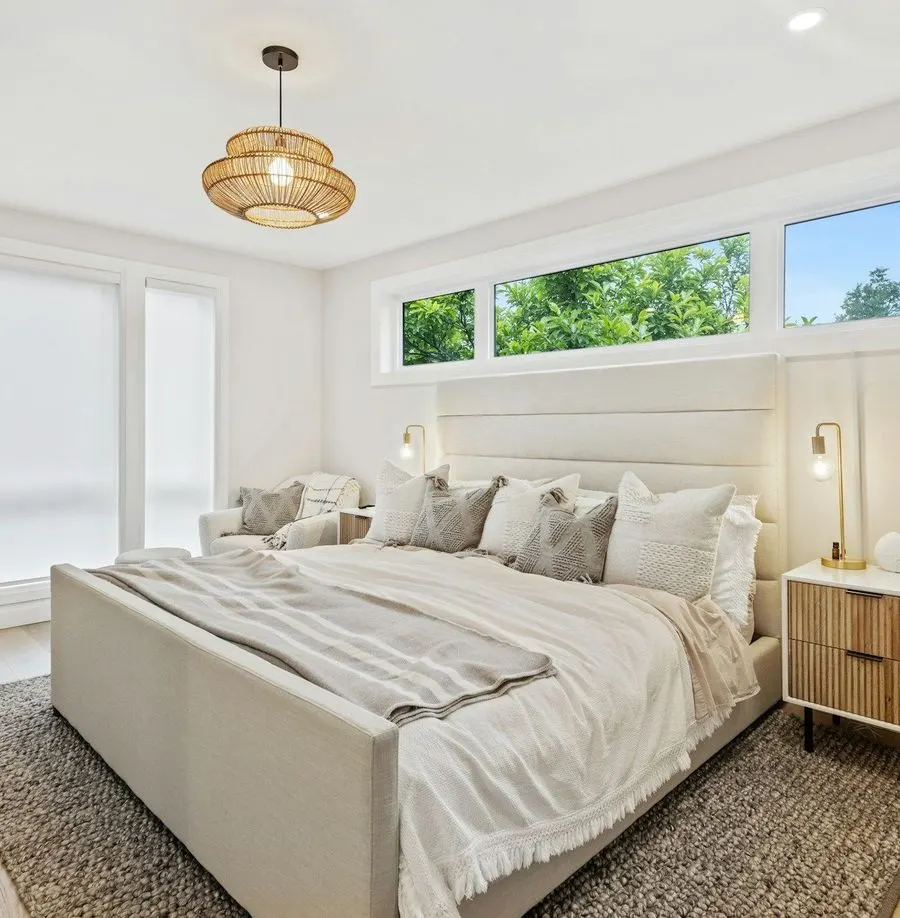 Bright bedroom with the bed made and high windows