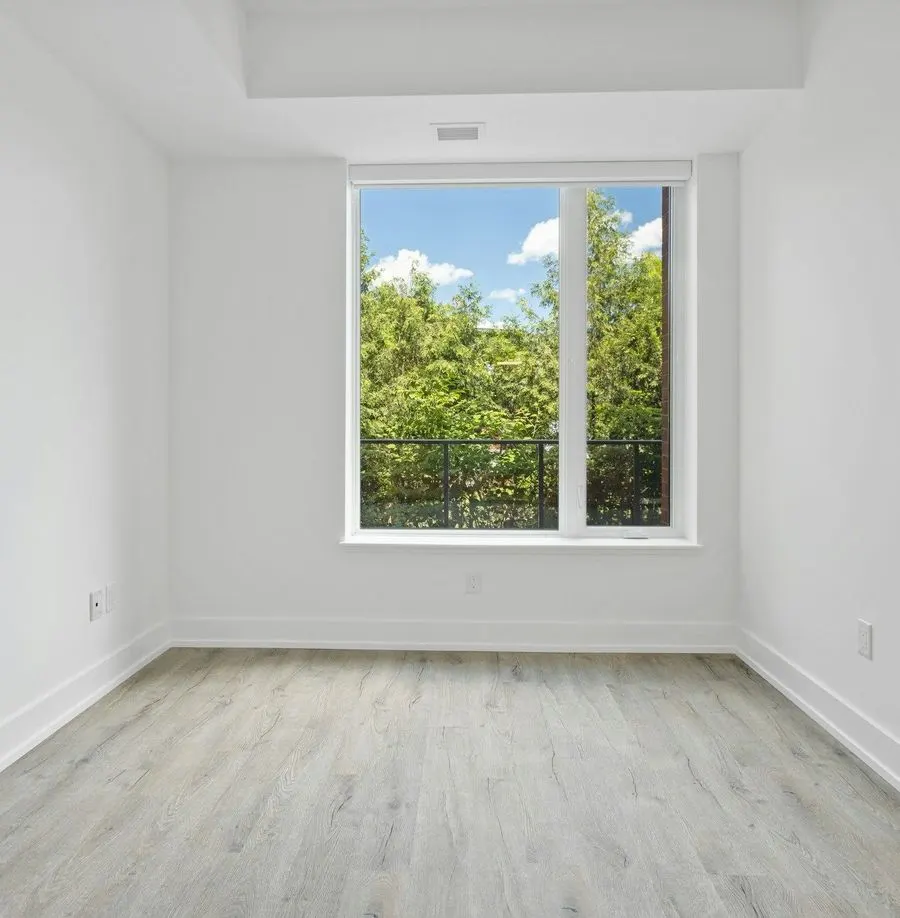 Empty white room with a clean floor and a window onto green trees