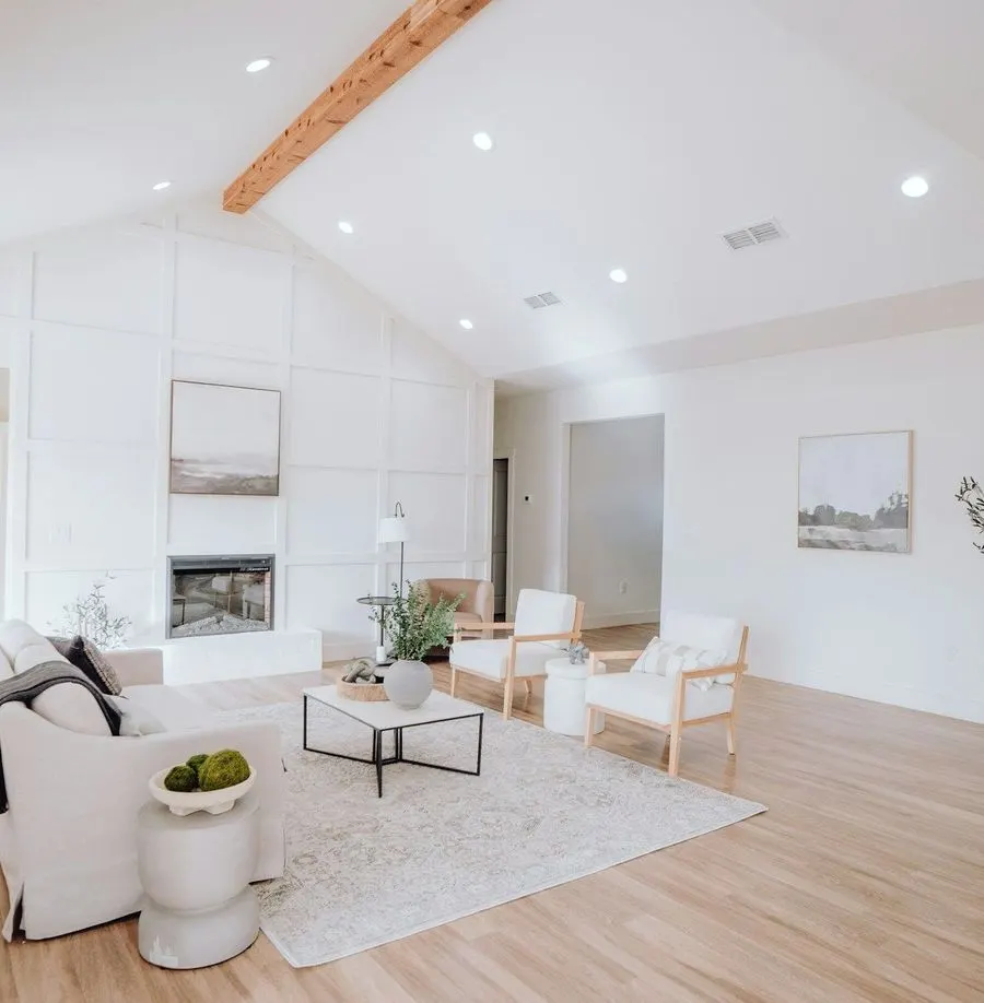 Wide, bright living room with white furniture and wood floors