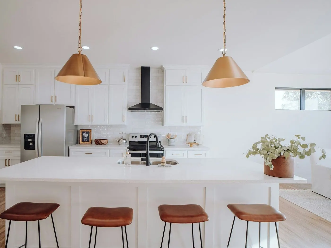 Clean white kitchen with an island and leather stools