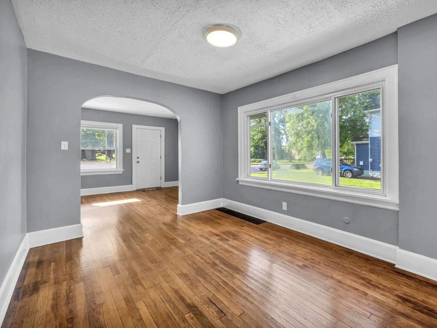 Empty room with gray walls, white trim and polished hardwood floors